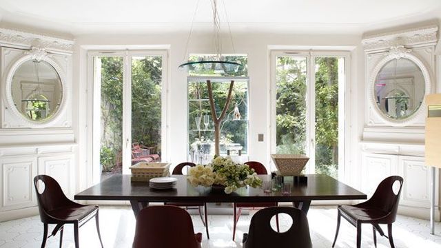 La salle à manger ouvre sur une terrasse-jardin. Les miroirs et stucs xixe ont été conservés. Sur la table en wengé, coupes en marbre d'Ettore Sottsass : "Crestino Mauryan" (à gauche) et "Bharata" (à droite). Chaises en bois laqué de Michele De Lucchi (Design Gallery Milano). Au-dessus de la table, suspension de Michele De Lucchi, collection "Ready Made" (Produzione Privata).